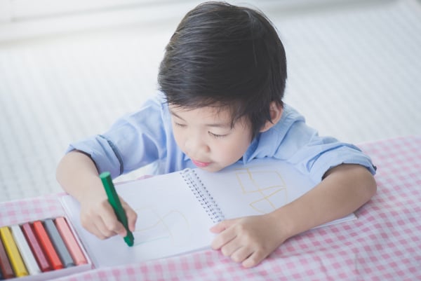 Asian child drawing picture with crayon