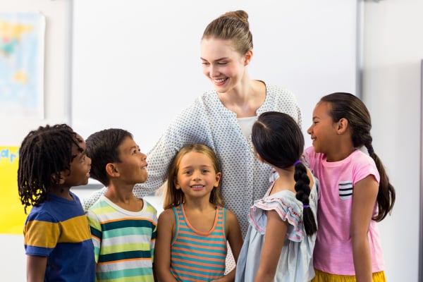 Smiling female teacher with schoolchildren in classroom
