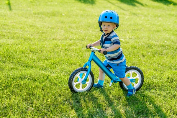 Boy in helmet riding a blue balance bike (run bike)