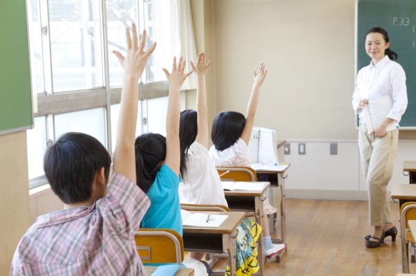 授業中挙手をする小学生4人の後ろ姿